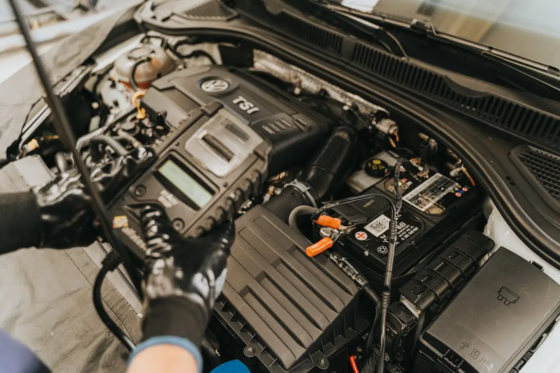 A technician using a diagnostic tool to register a new battery with the car's computer system and on-board electronics.
