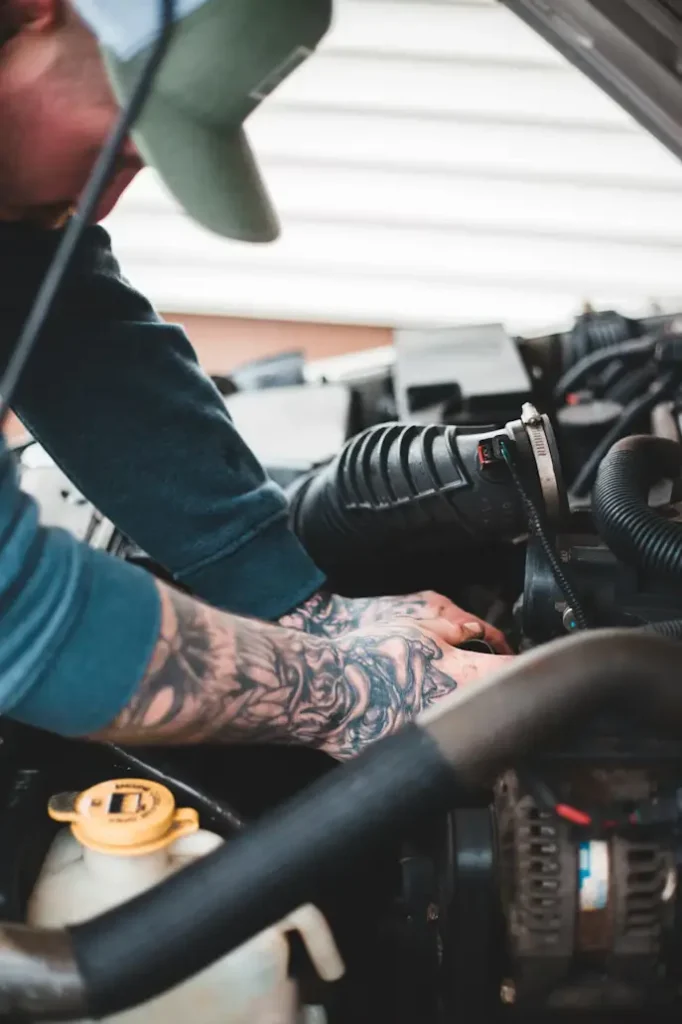 A mobile engineer removing an old car battery safely and preparing to fit a new, correctly specified replacement.