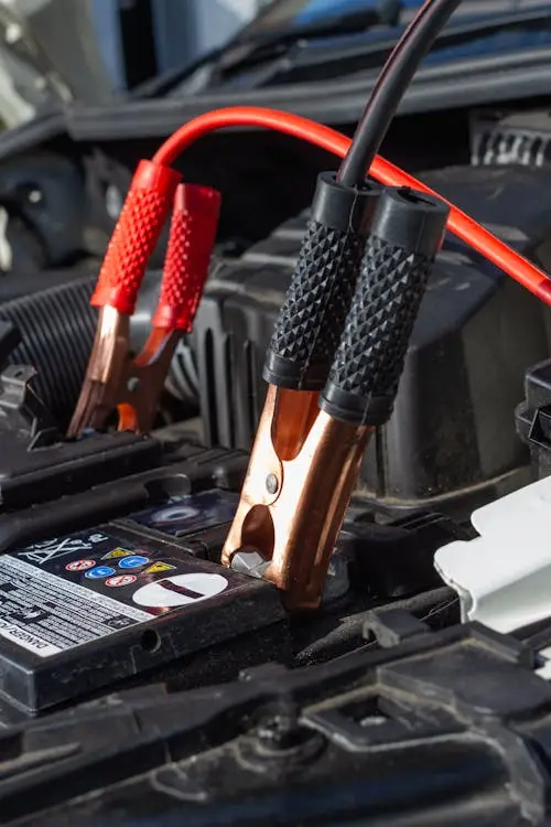 Technician performing a mobile car battery jump start service